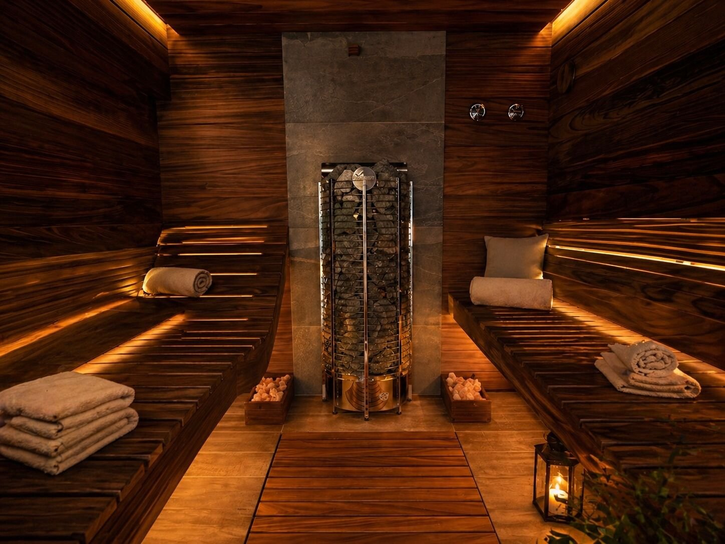 Private sauna with warm walnut interior, folded towels and a glowing lantern
